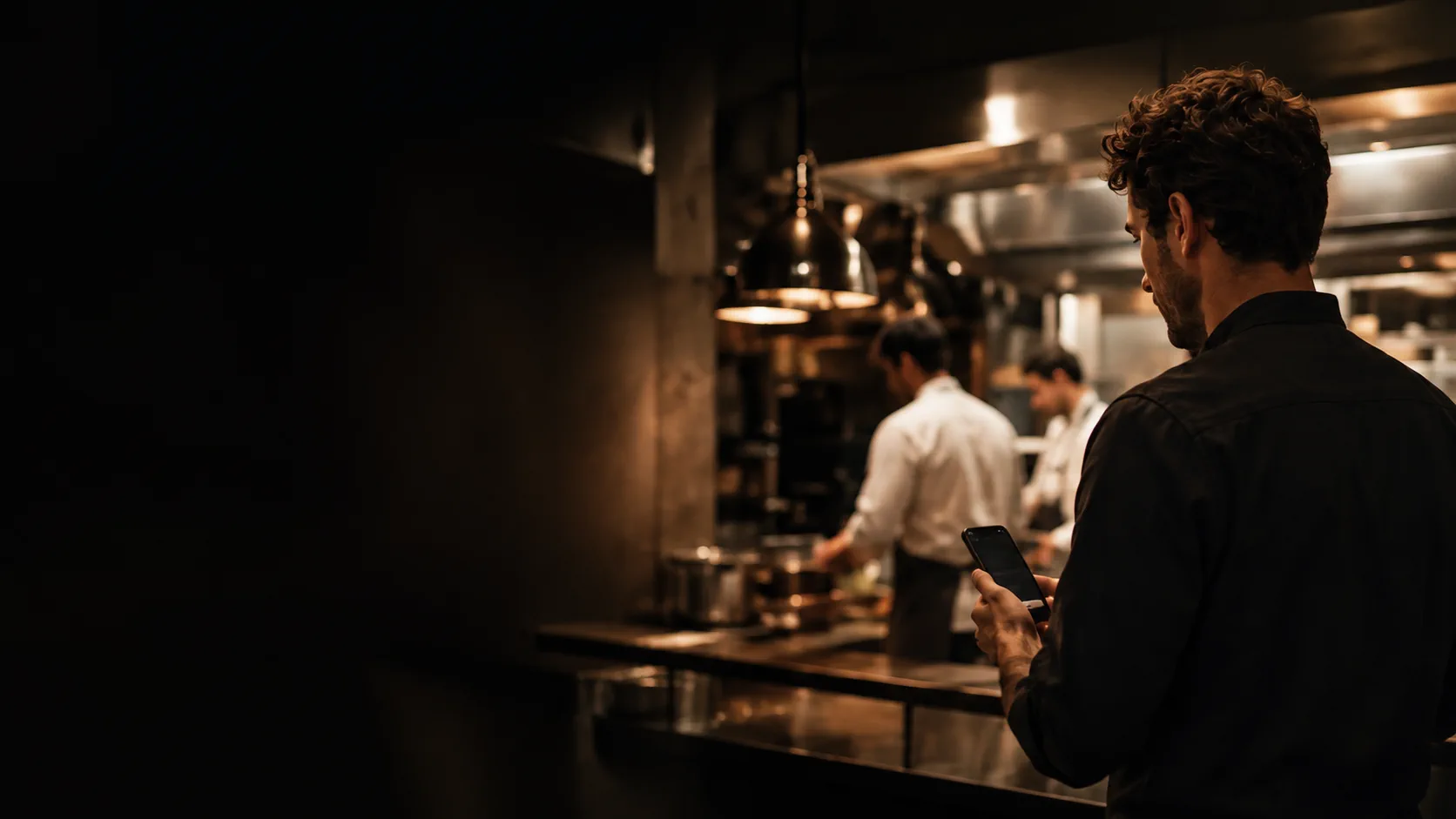 Un professionnel consulte son téléphone dans un restaurant en activité.